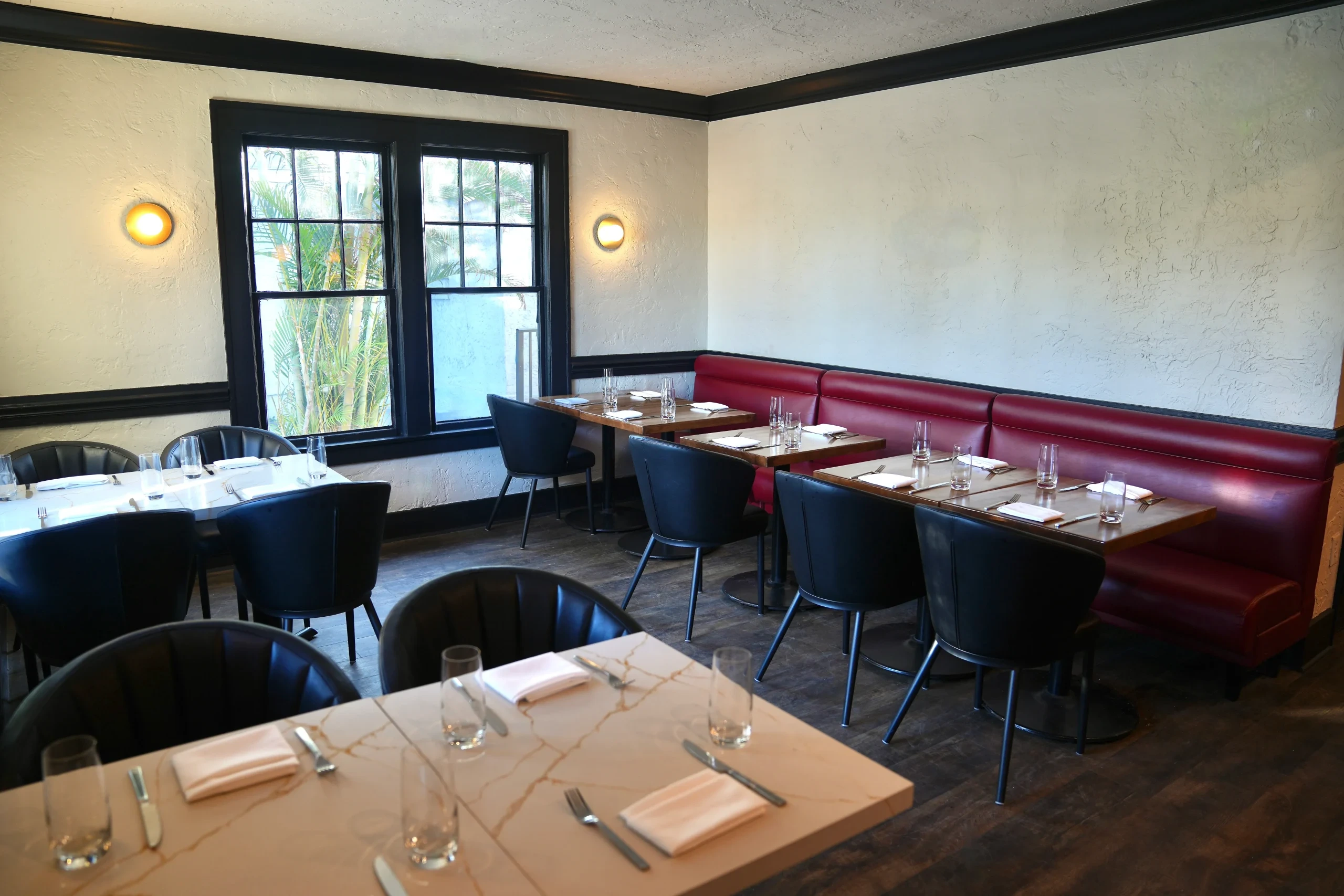 Tables and red banquettes in Novecento Delray Beach
